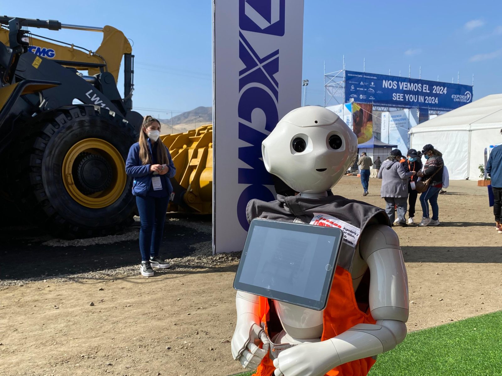 El robot Pepper con chaleco reflectante atendiendo en una feria industrial al aire libre
