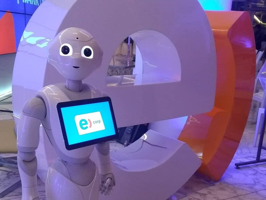 El robot Pepper en el estand de una marca, con el logo del cliente en la pantalla de su pecho